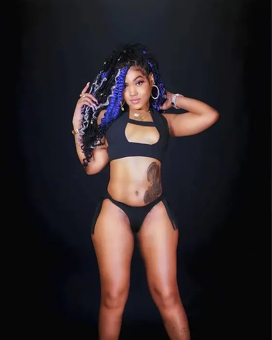 Kerina Alex wearing a black bikini and purple braided hair with hoop earrings for the GrindHard MixShow schedule